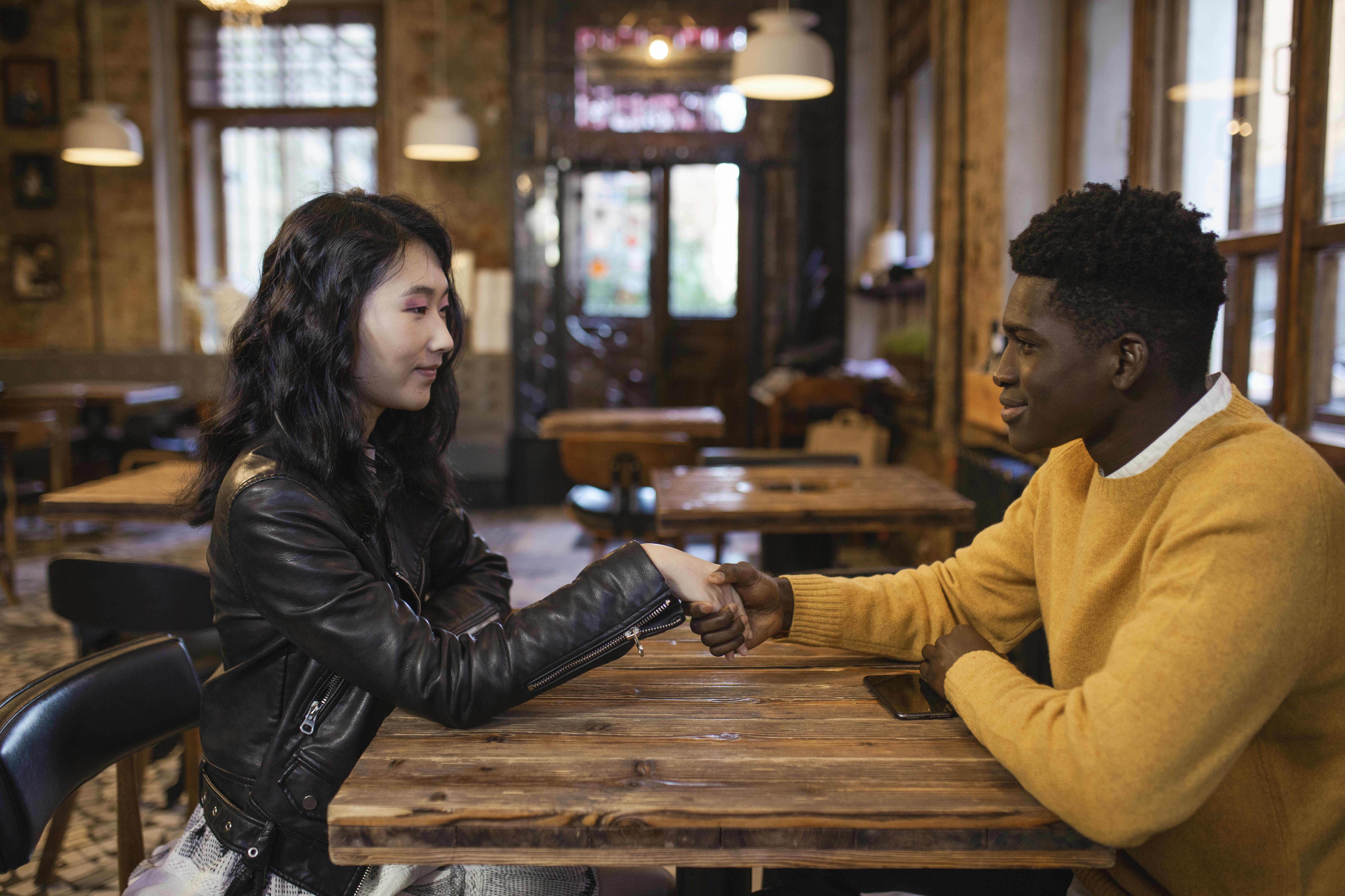 a man and woman sitting near the wooden table while holding hands