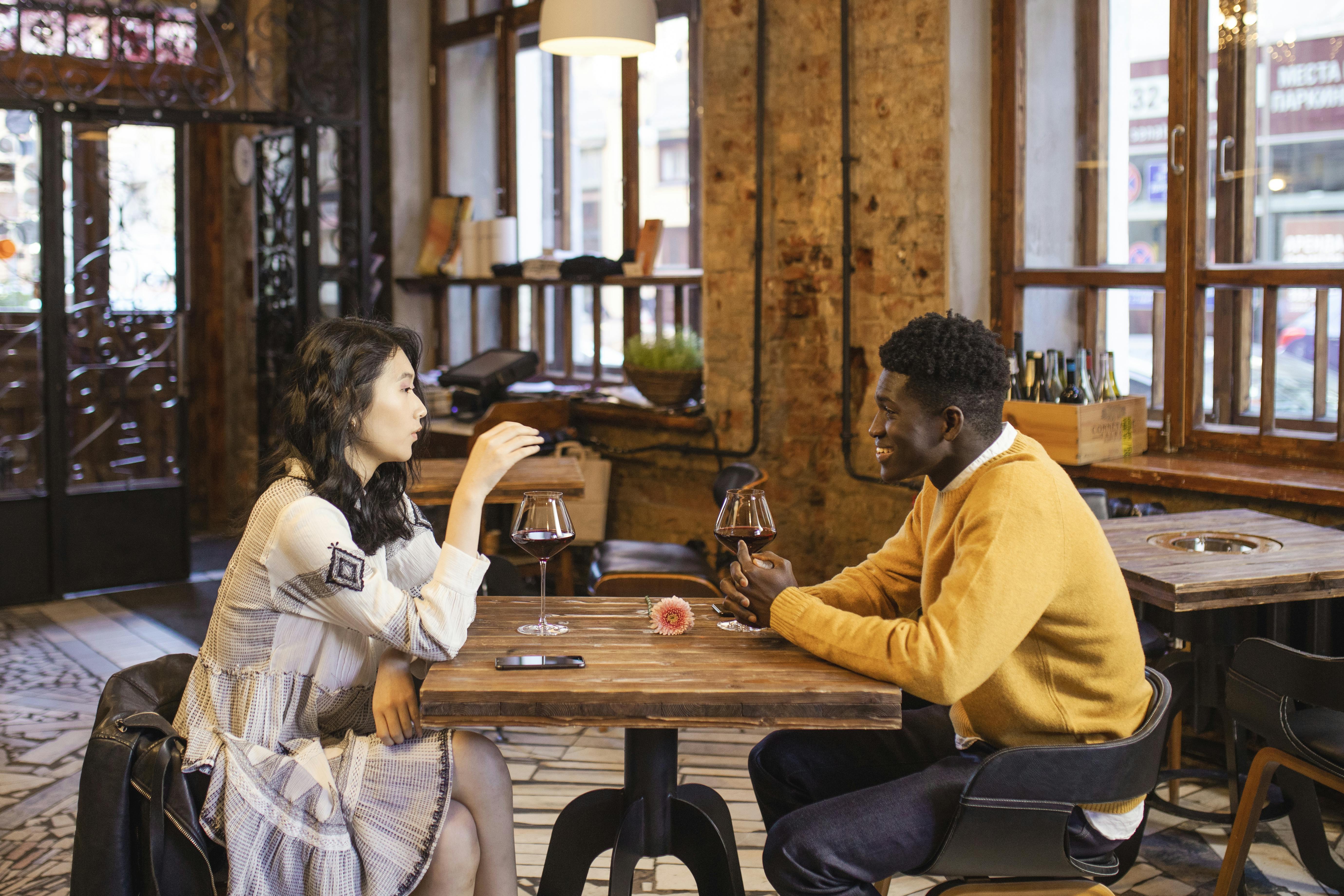 A couple shares a romantic date with wine at a cozy restaurant, highlighting diverse relationships.