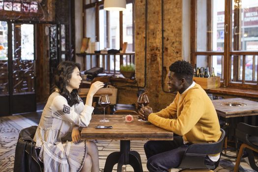 A couple shares a romantic date with wine at a cozy restaurant, highlighting diverse relationships.