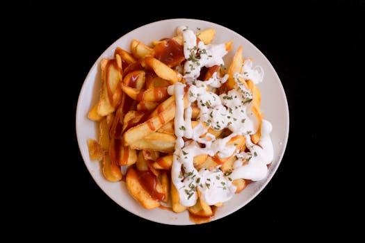 A plate of crispy fries topped with creamy sauce and herbs, perfect as a delicious snack.