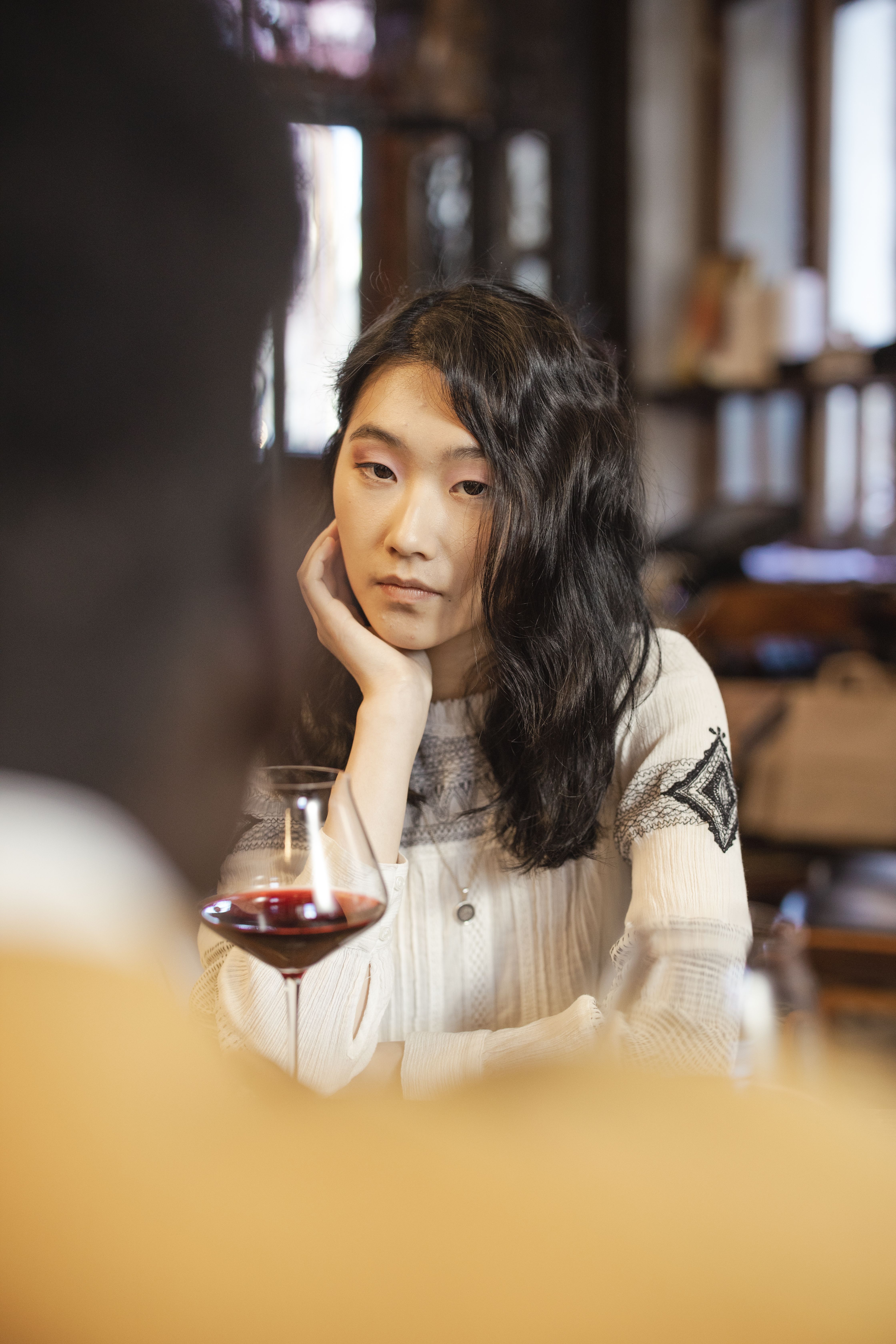 Emotionless Woman sitting beside a Wine Glass · Free Stock Photo