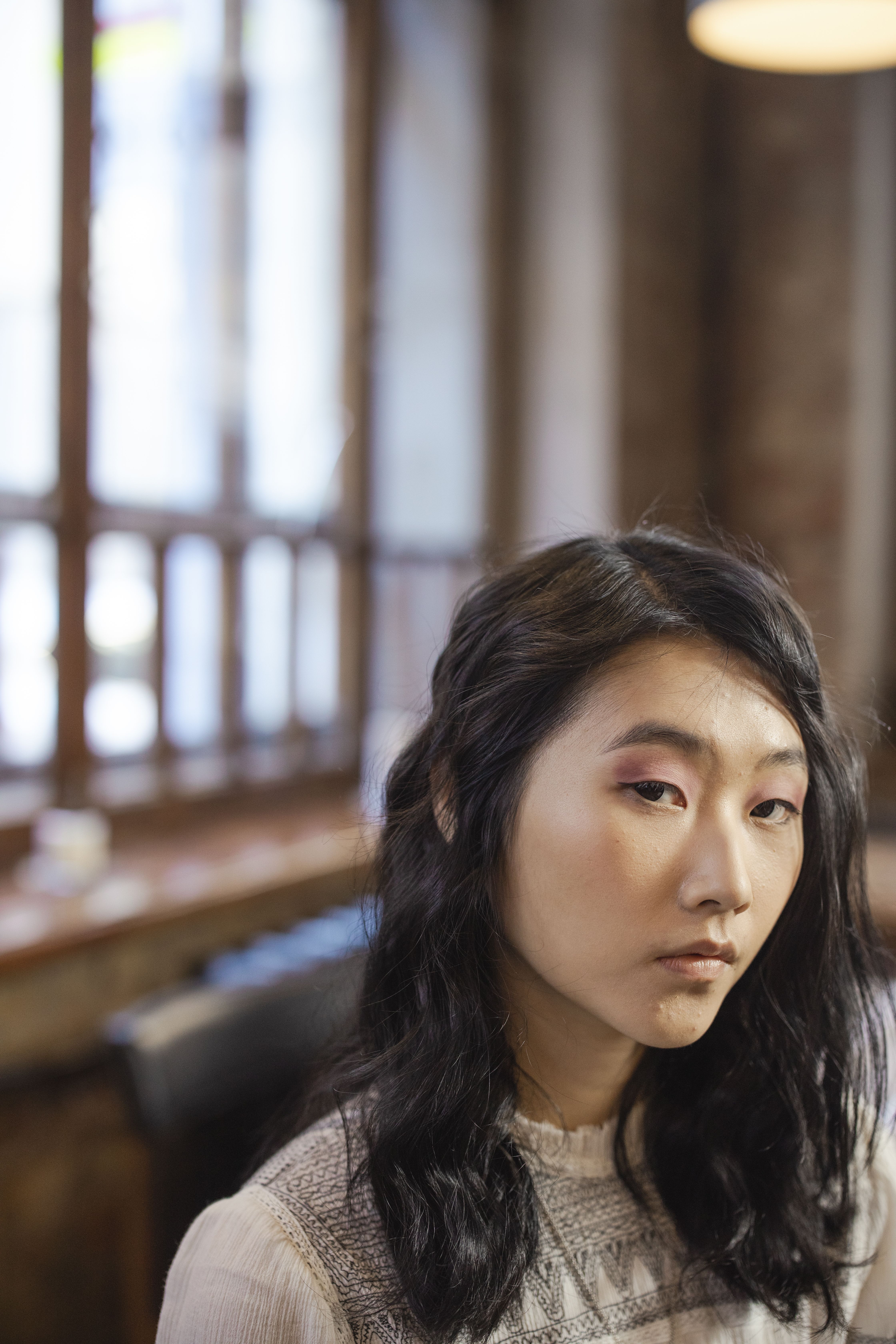 Thoughtful portrait of a woman with black hair, captured in a softly lit indoor setting.