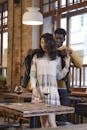 Man in Black Leather Jacket Hugging Woman in White and Brown Dress