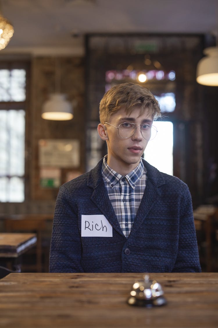 A Man Wearing A Blazer With A Name Tag