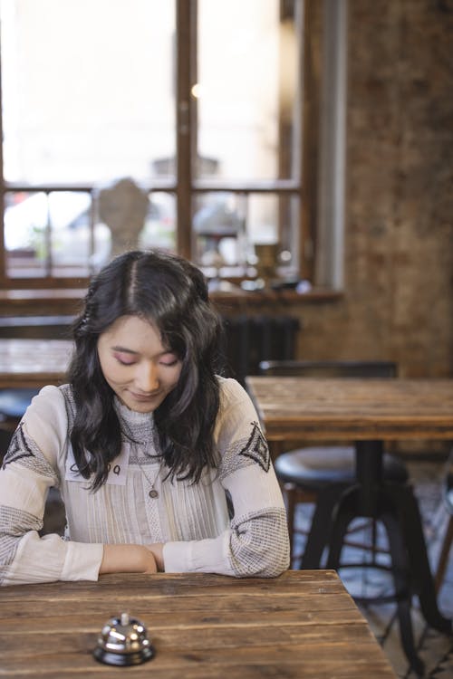 Free Shy Woman sitting across the Wooden Table  Stock Photo