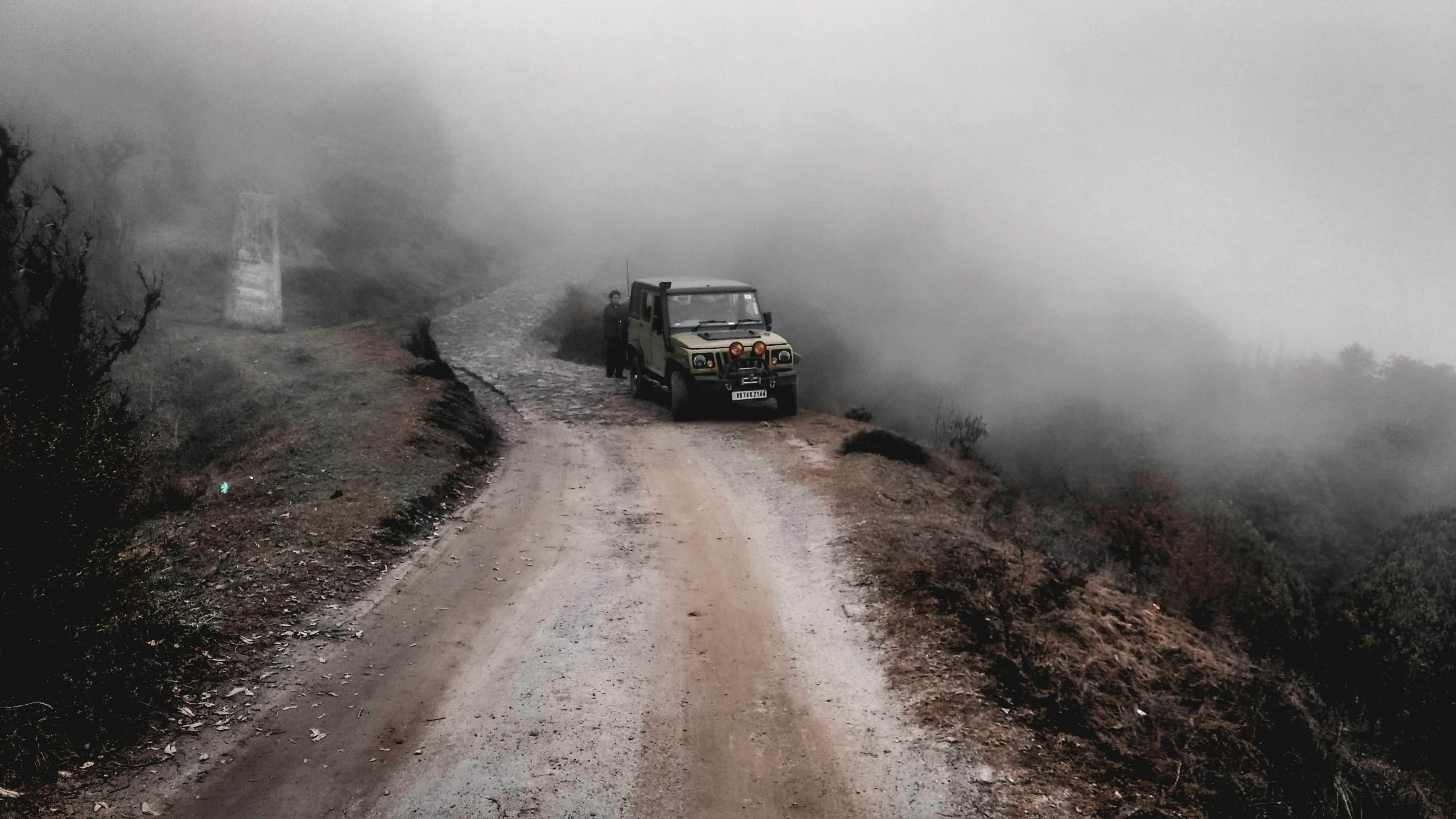 Off-road vehicle on a foggy mountain dirt trail showcasing adventure and exploration.