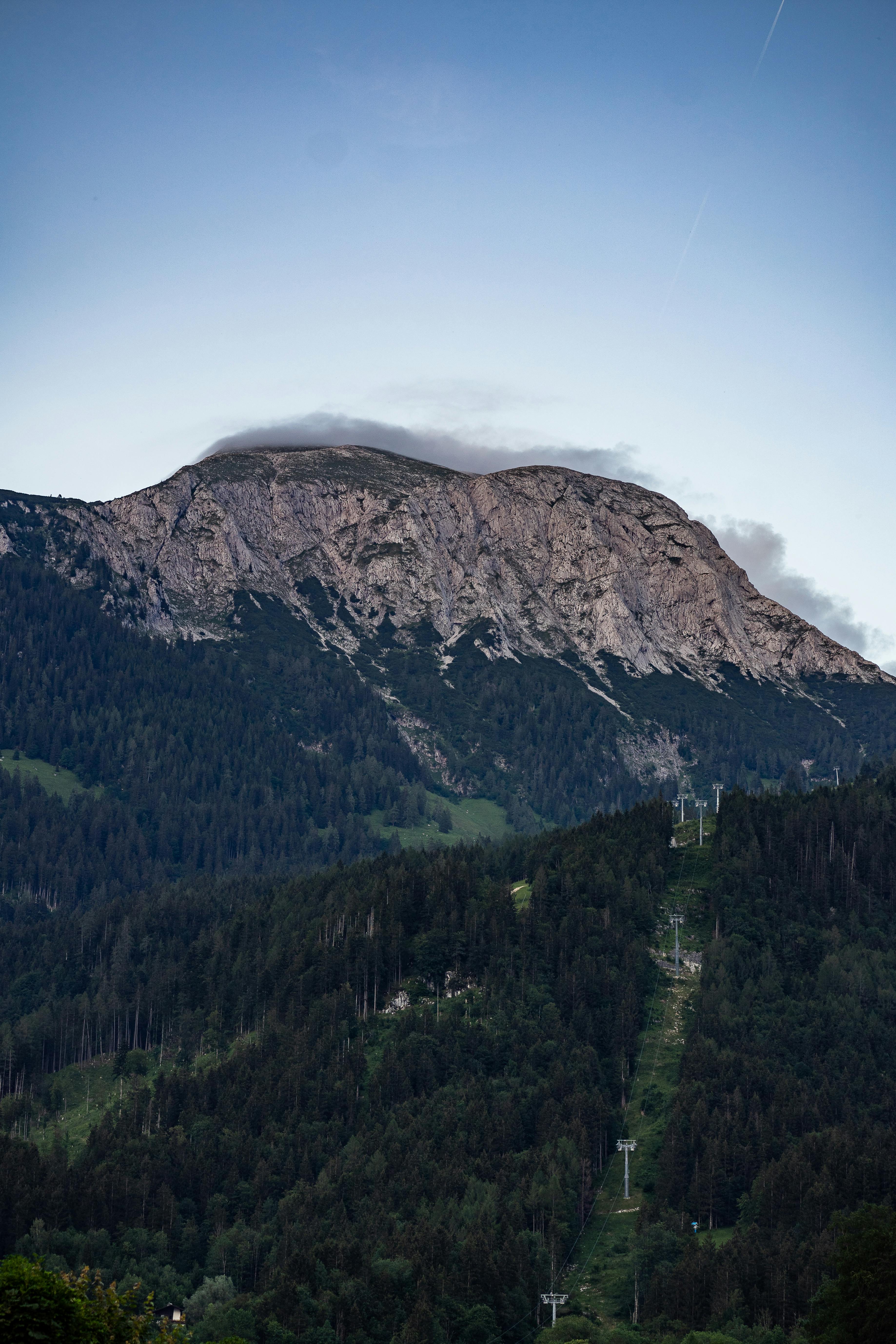 A stunning mountain landscape with cable cars amidst forested slopes at dusk.