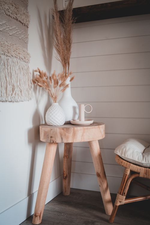 Free Wooden tripod table with decorated vases of ears and stool with pillow standing in corner of light room Stock Photo