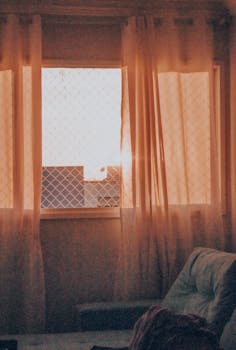Warm light filters through curtains, creating a cozy indoor ambiance during sunset.