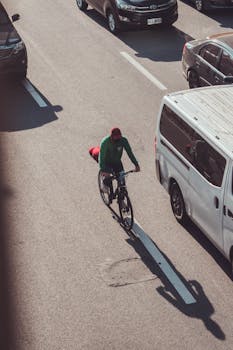 A cyclist in Makati, Philippines riding amidst busy traffic on a sunny day.