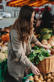 A woman picking fresh vegetables at an outdoor market in Erfurt, Germany.