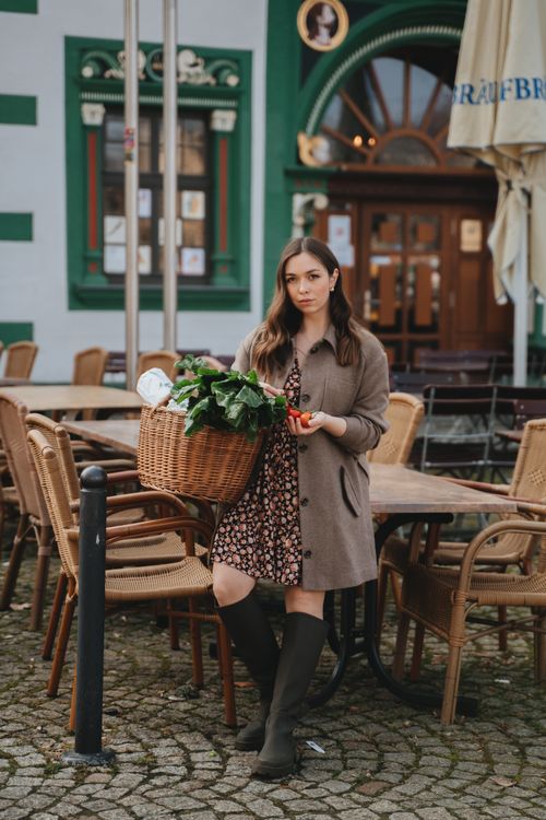 Free A woman holds a basket filled with vegetables on a cobblestone street in Erfurt, Germany. Stock Photo