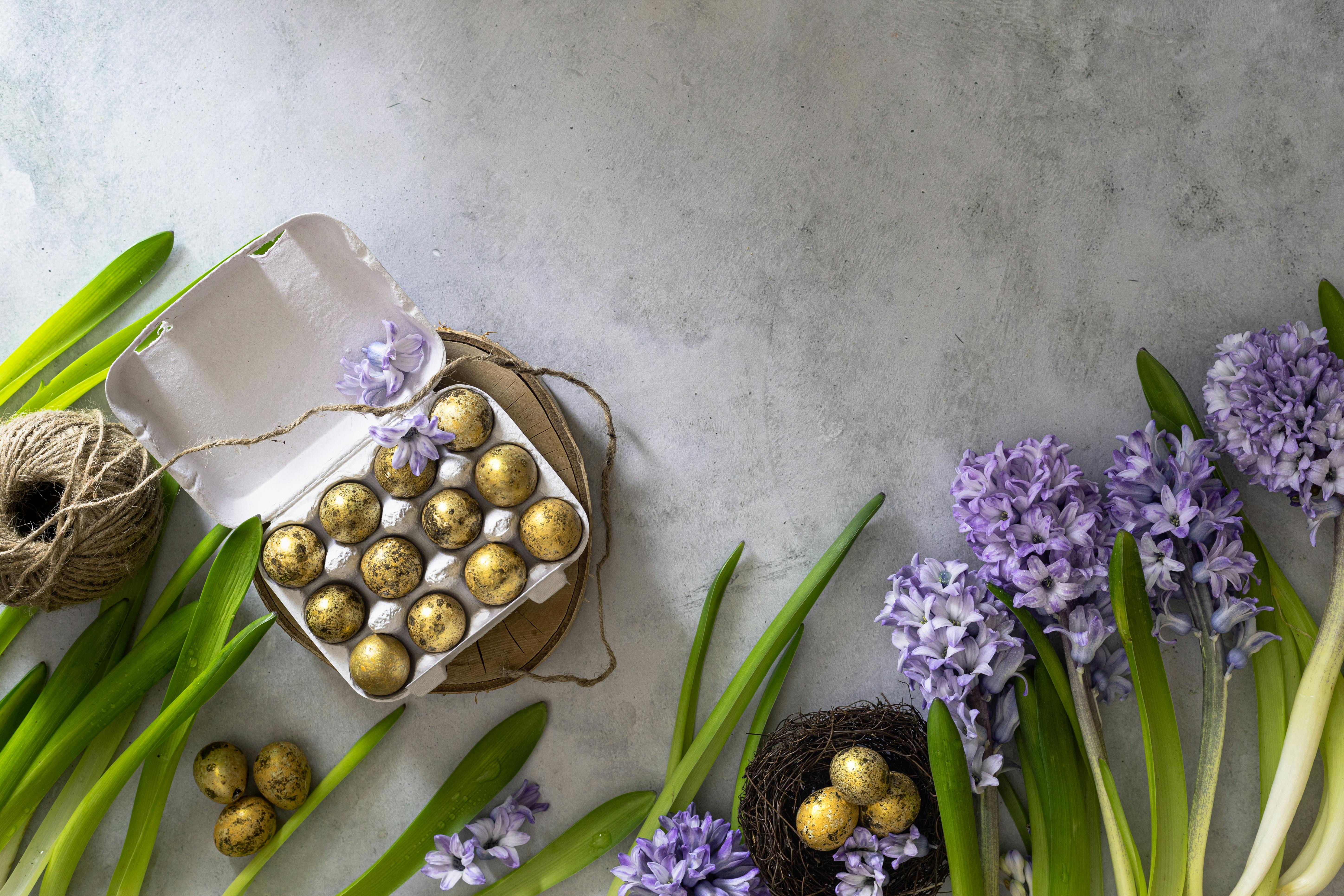 Spring-themed flat lay with purple hyacinth flowers, quail eggs in a carton, and natural string.
