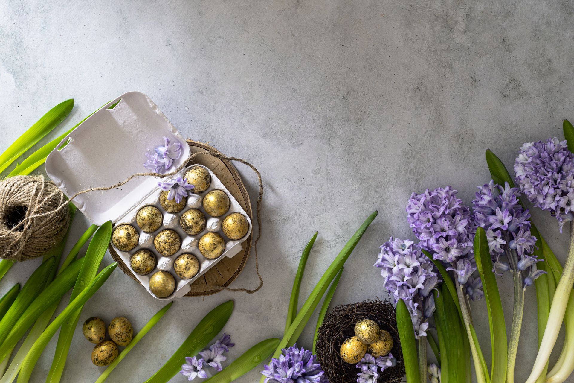 Spring-themed flat lay with purple hyacinth flowers, quail eggs in a carton, and natural string.