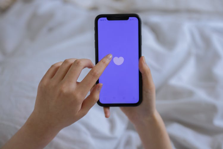 Person Using Cellphone In Bed