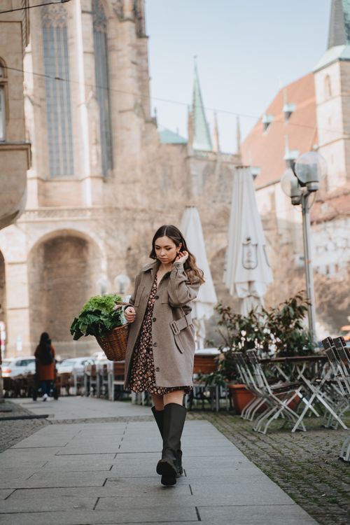 Free Young woman strolling with a basket beside cafes in historic Erfurt. Stock Photo