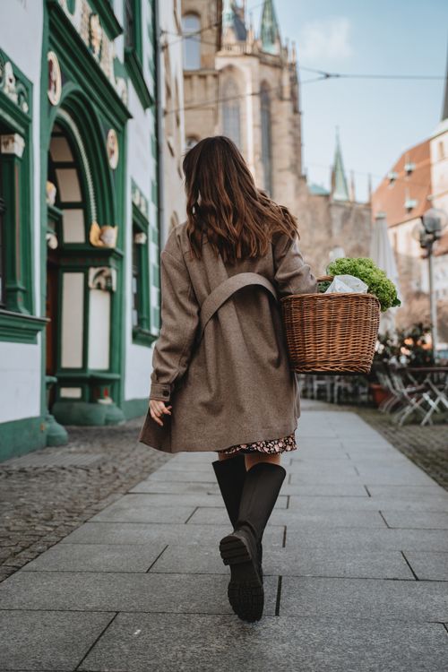 Free A woman carrying a basket of fresh vegetables walks through a charming street in Erfurt, Germany. Stock Photo