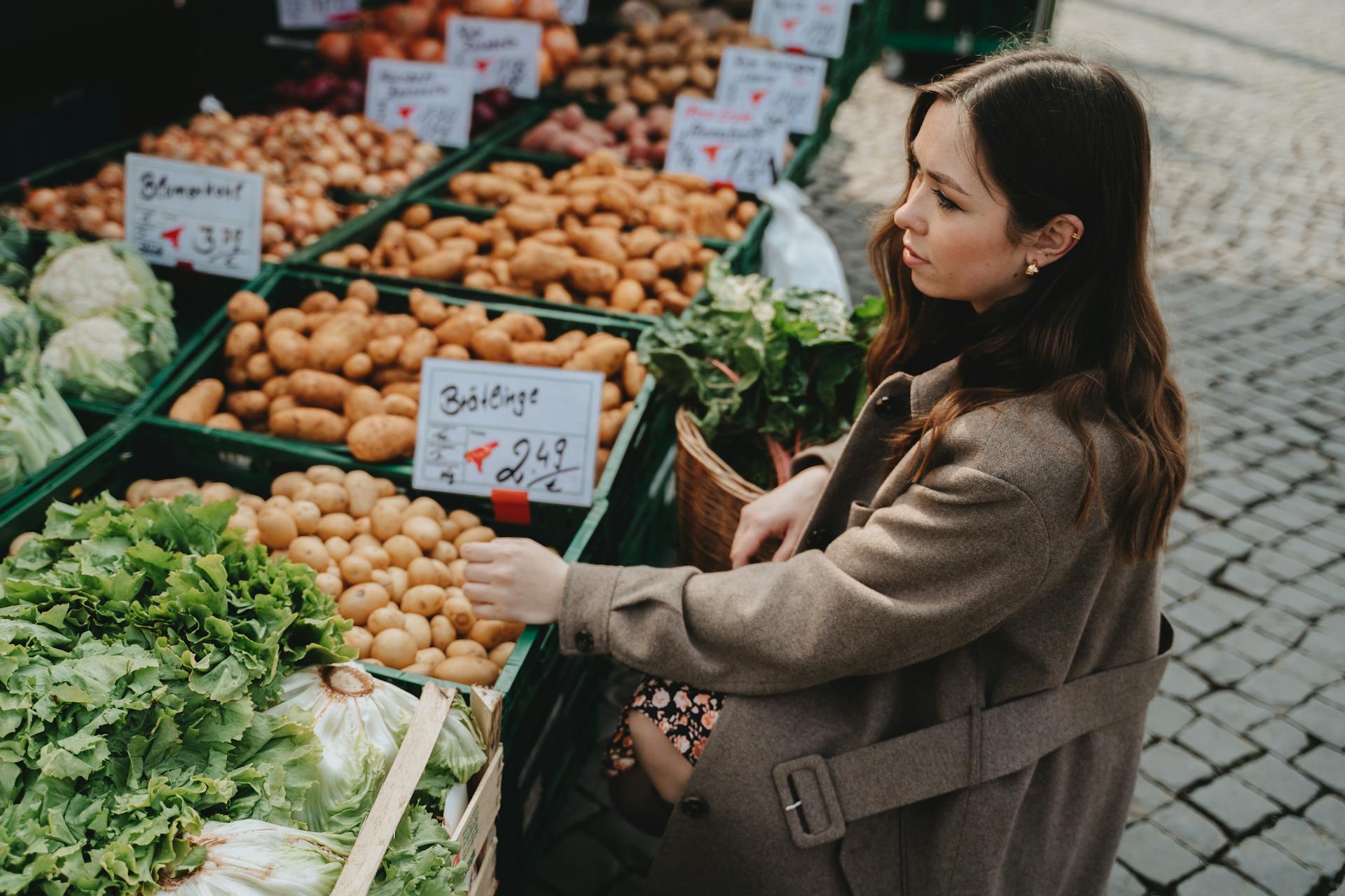 Young woman shopping for fresh vegetables at an outdoor farmers market in Erfurt, Germany.