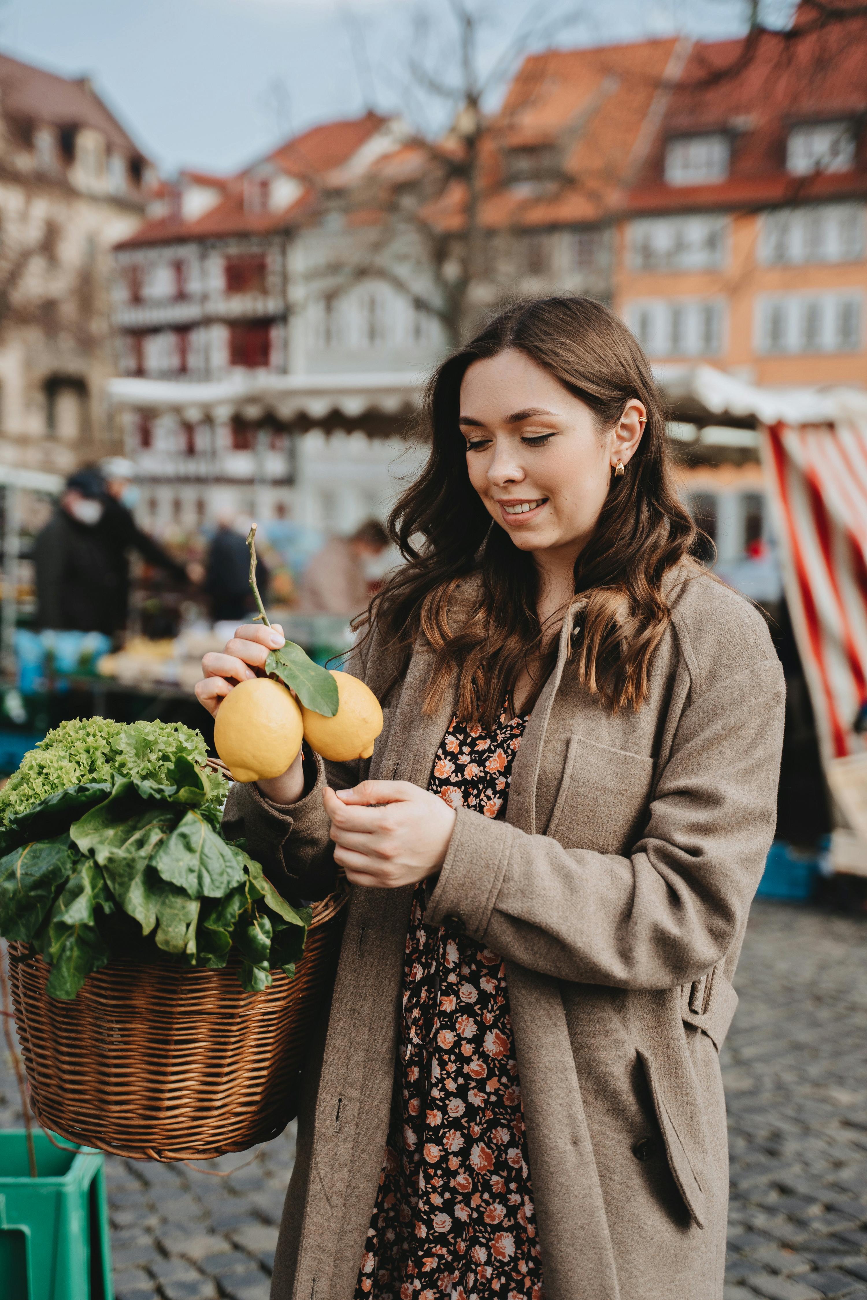 photo of a woman in a coat holding yellow lemons