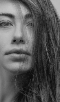 Black and white close-up portrait of a woman with expressive eyes and flowing hair.