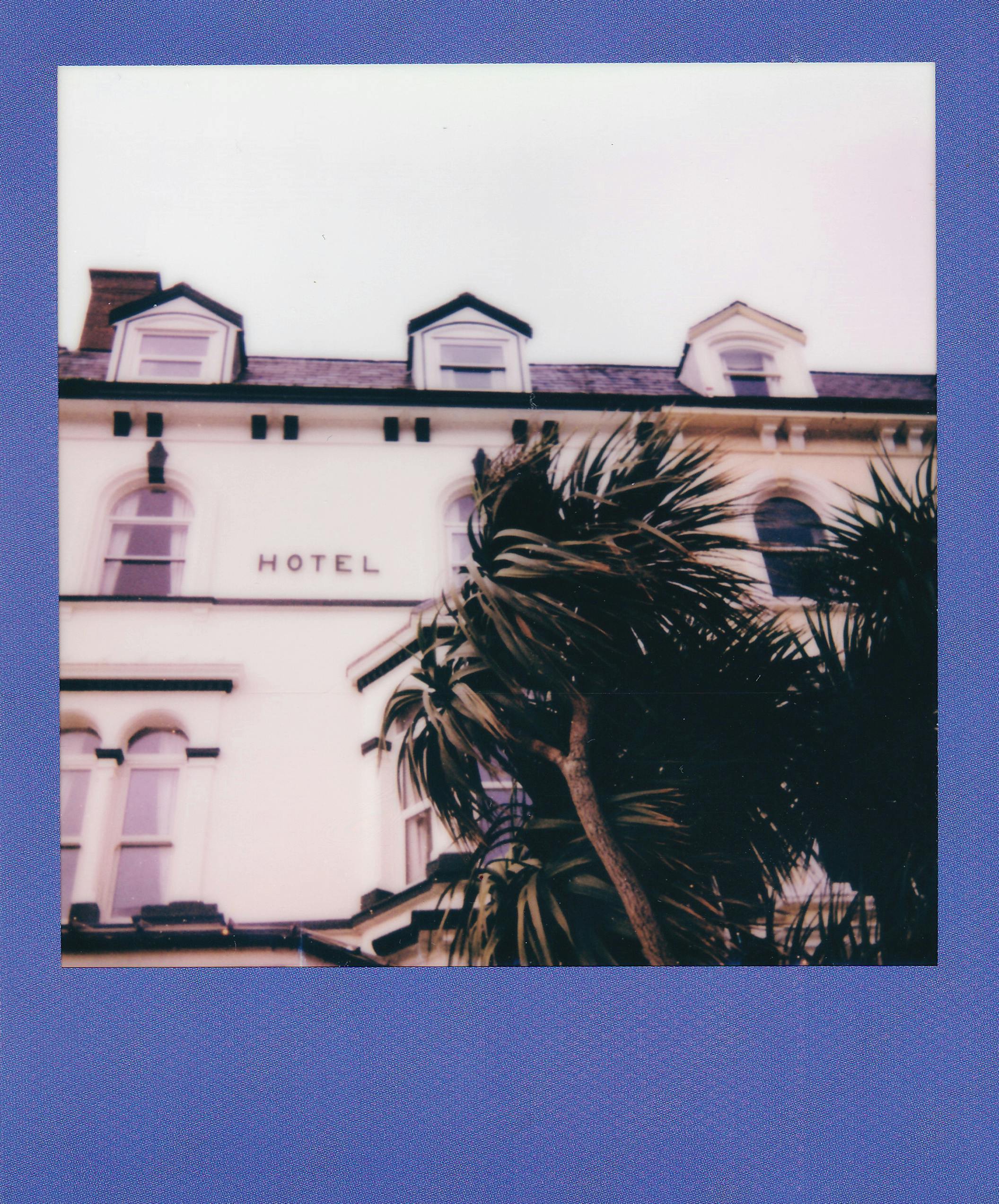 A retro-style Polaroid photograph capturing the facade of a classic hotel with palm trees.