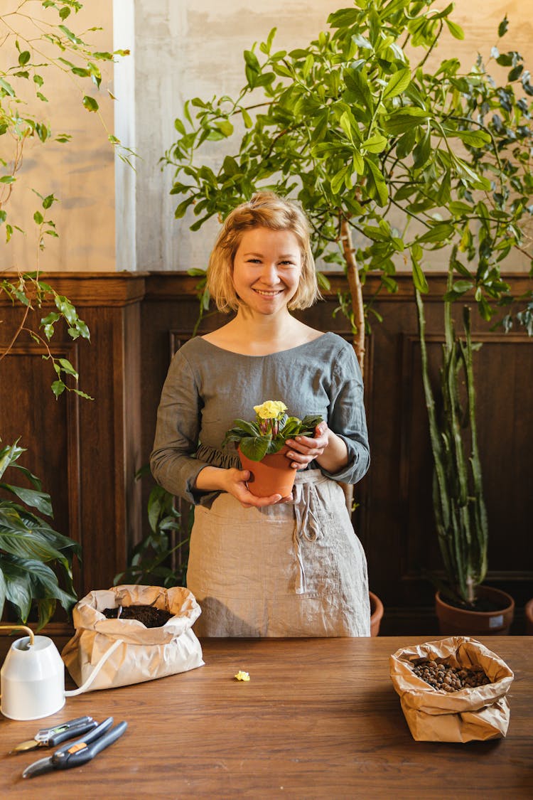 Photo Of A Woman With Blond Hair Holding A Pot With A Flower