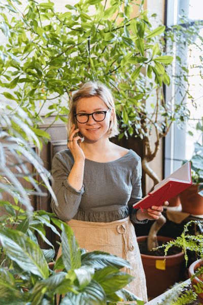 Smiling gardener on a phone call, notebook in hand