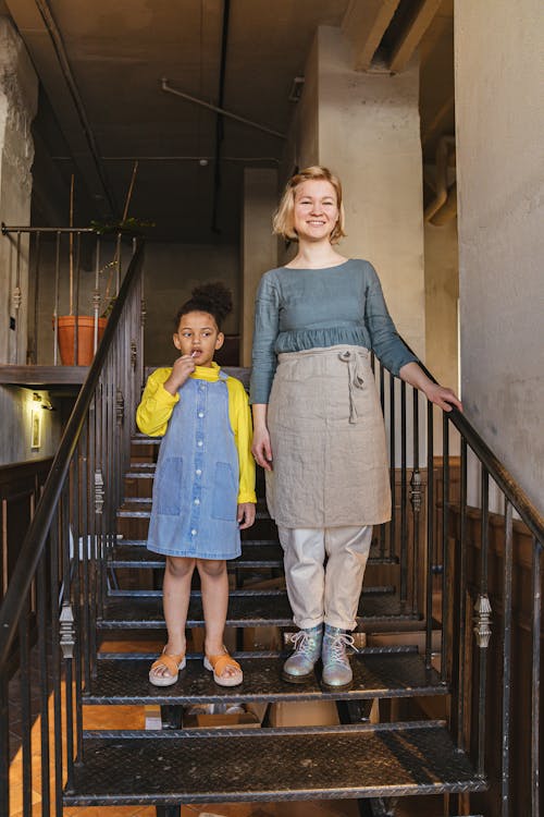 Free A Child and a Woman Standing on a Stairway Stock Photo