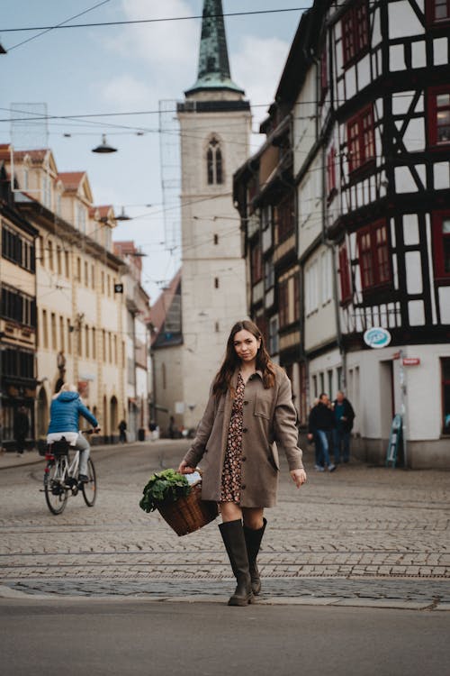 Woman in Brown Coat and Black Skirt Walking on Sidewalk