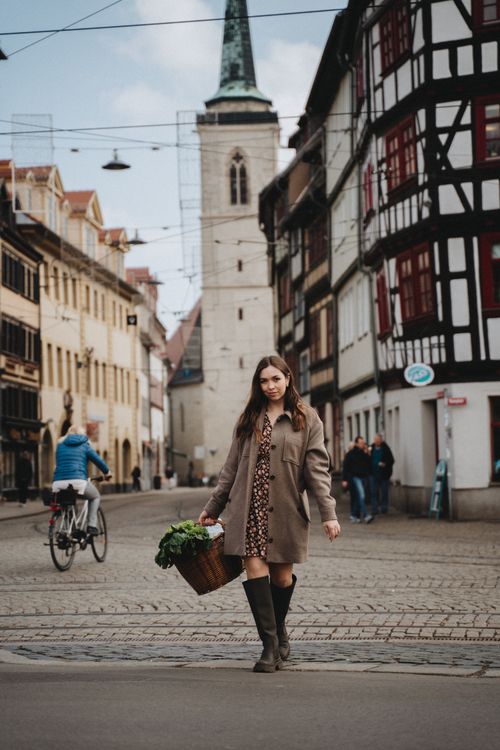 Free A woman in a brown coat walks with a wicker basket on a picturesque street in Erfurt, Germany. Stock Photo