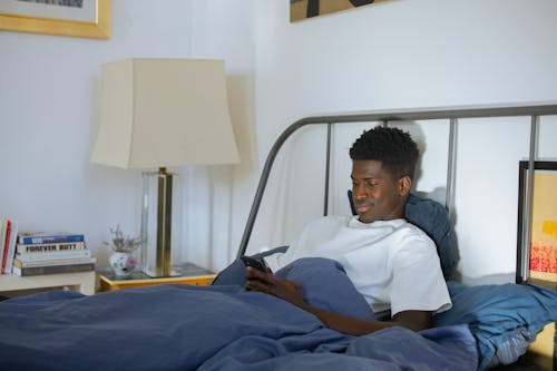 Man Using Phone while on Bed