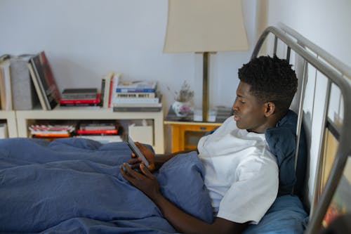 Man Using Phone while on Bed