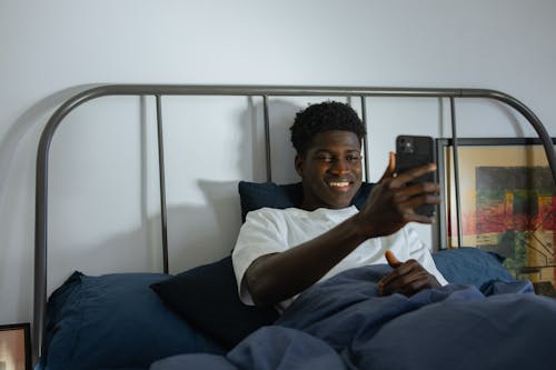 Man Lying on Bed while having a Facetime Session 