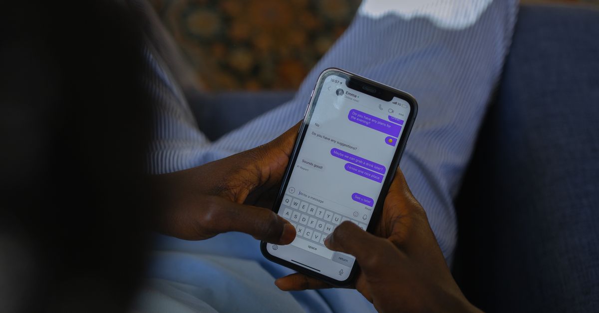 Close-up of hands holding a smartphone, typing a message on the touch screen