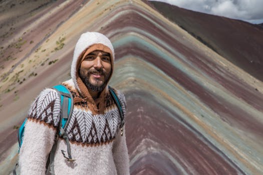 A smiling man in a cozy sweater at Rainbow Mountain in Peru, a popular travel destination.