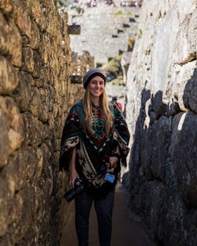 Smiling photographer wearing a traditional poncho standing in ancient stone ruins in Peru.