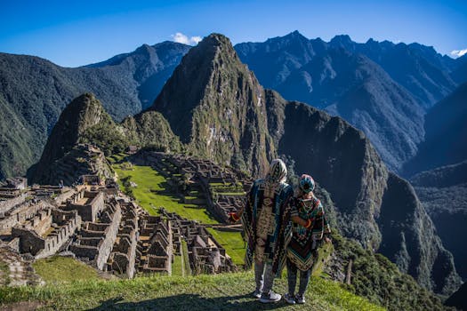 A couple in traditional ponchos admire the breathtaking view of Machu Picchu in Peru.