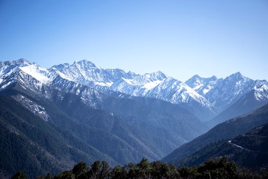 Breathtaking view of snow-capped mountains under a clear blue sky in Sichuan, China.