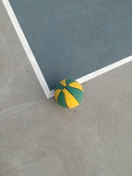 A colorful basketball resting on a court corner. Ideal for sports themes.