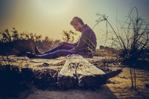 Man Sitting Near Brown Wood Plank