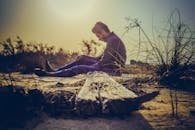 日落时分，一个人独自坐在沙地上，在自然的宁静中感受孤独