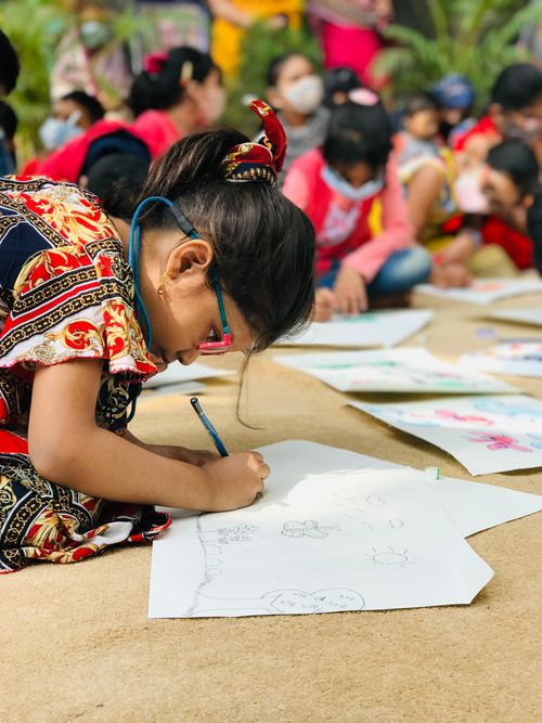 Free A young South Asian girl focuses on drawing during an outdoor event in Dhaka, Bangladesh. Stock Photo