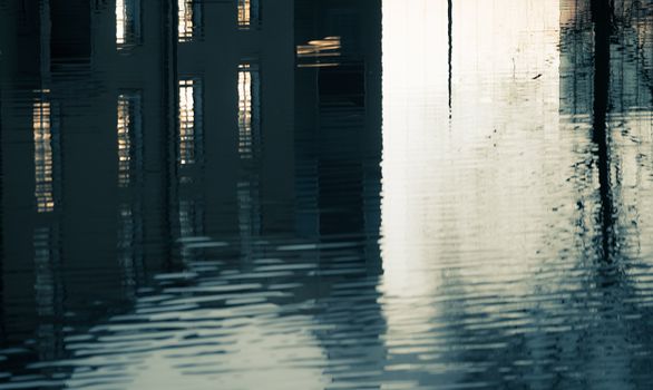 A serene reflection of urban buildings on a rippling water surface, creating an abstract visual effect.