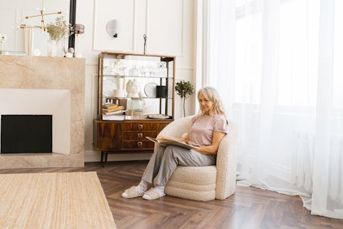 Elderly Woman Reading Book on Sofa Chair