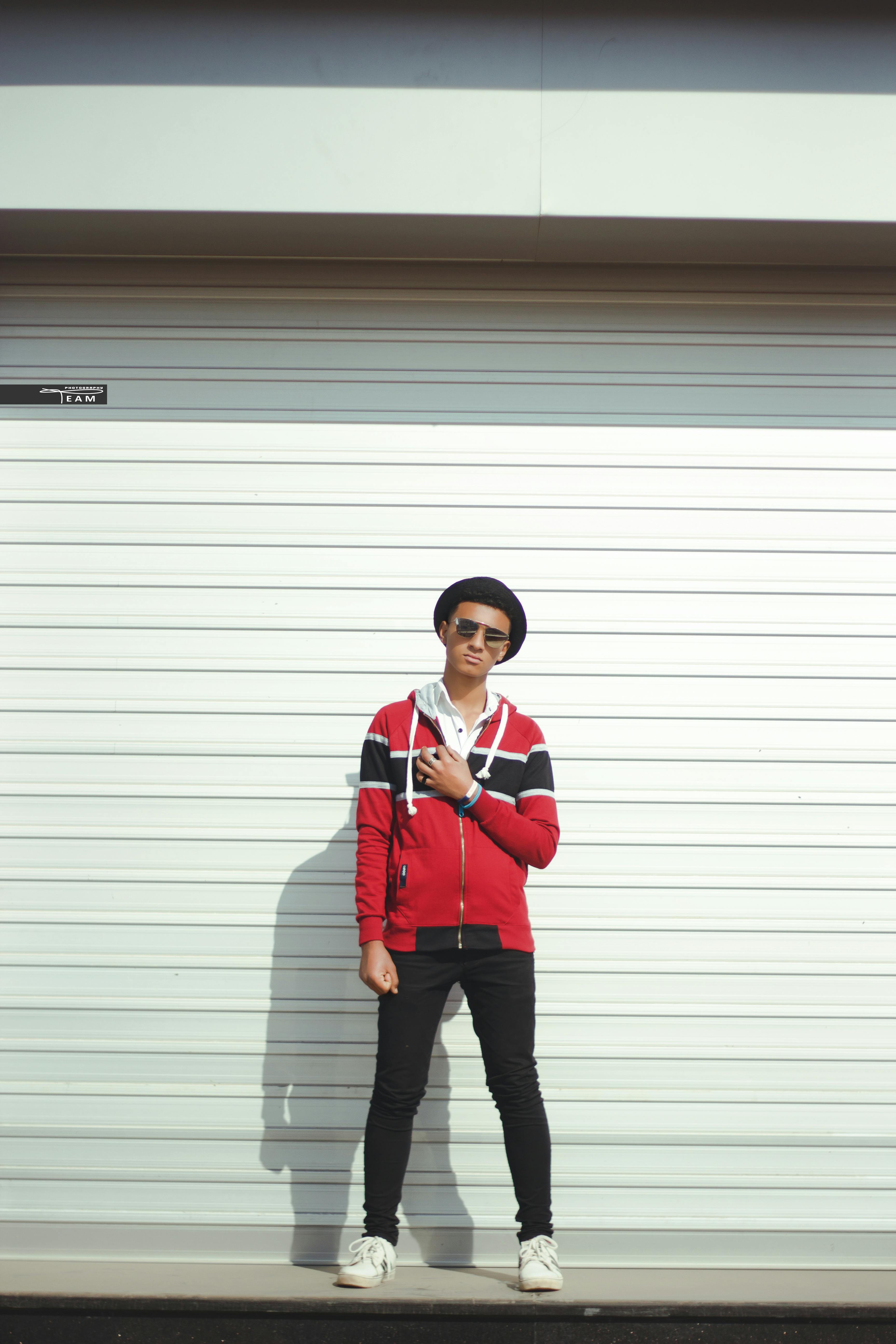 Man In Red And Black Zipup Jacket And Black Pants With Black Hat