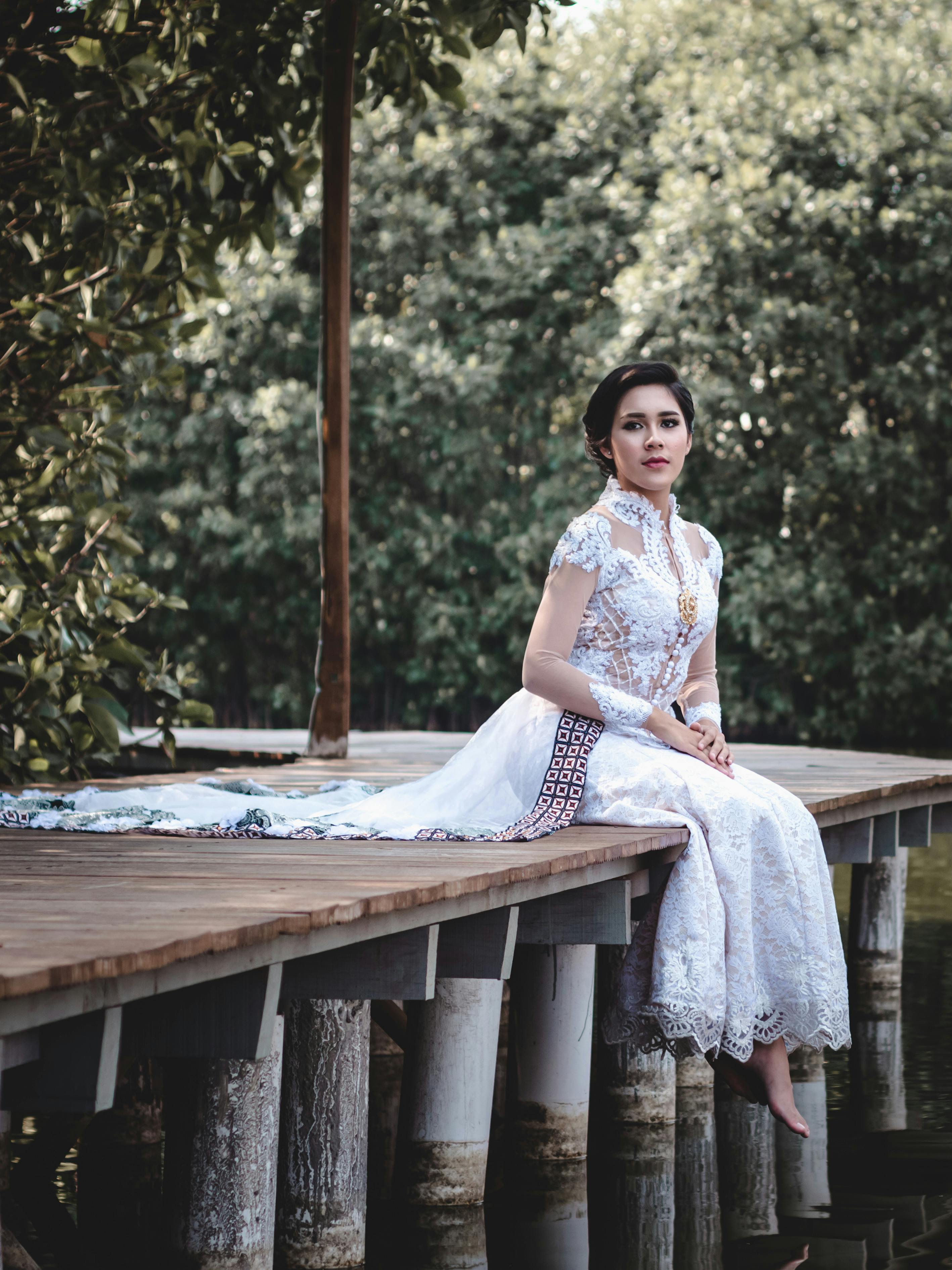 Woman in White Long Lace Dress Sitting on Wooden Dock · Free Stock
