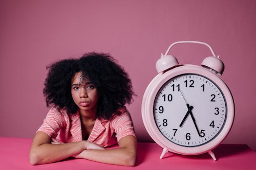 Woman Looking Bored Beside a Big Alarm Clock