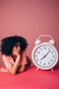 Woman Looking at a Big Pink Alarm Clock