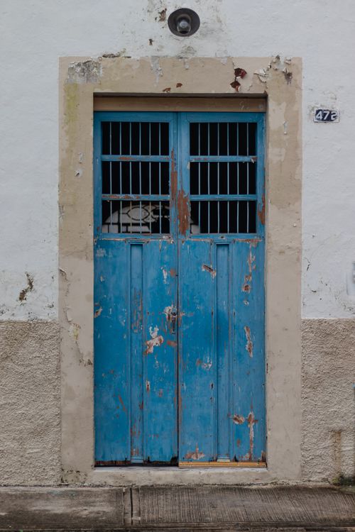 Free A rustic weathered blue door with peeling paint set in a textured white wall in Mexico. Stock Photo
