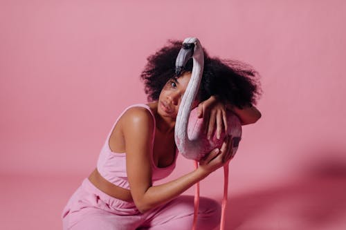 Woman in Pink Crop Top Holding onto a Pink Flamingo